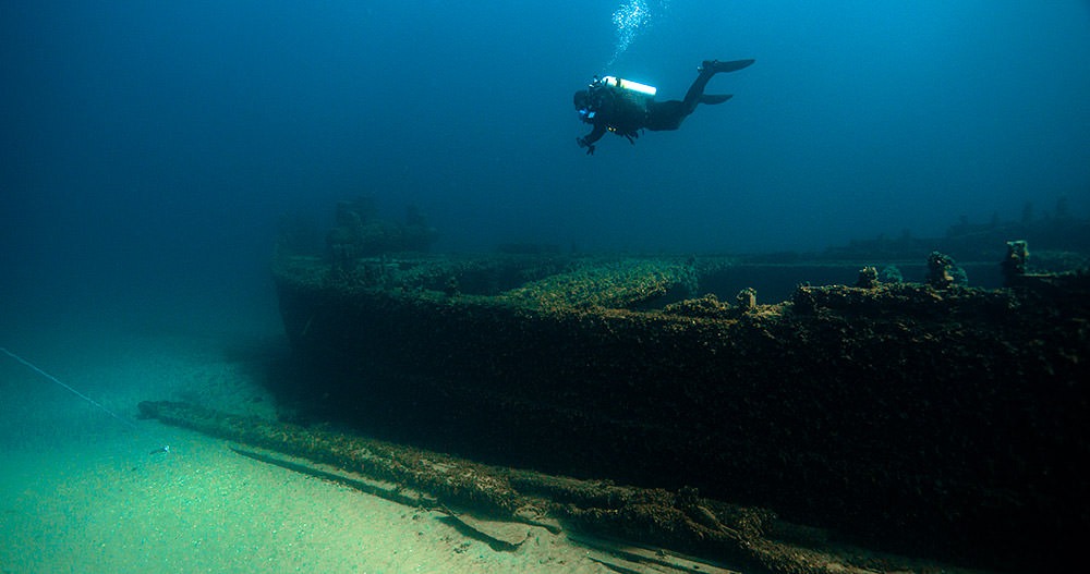 A scuba diver hovers over the wreckage of d.m. wilson