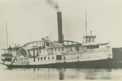 A black and white photo of an old paddle wheel ship