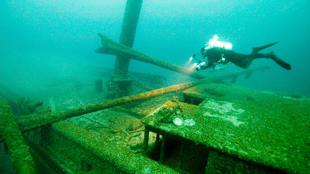 A diver shines a light on a shipwreck