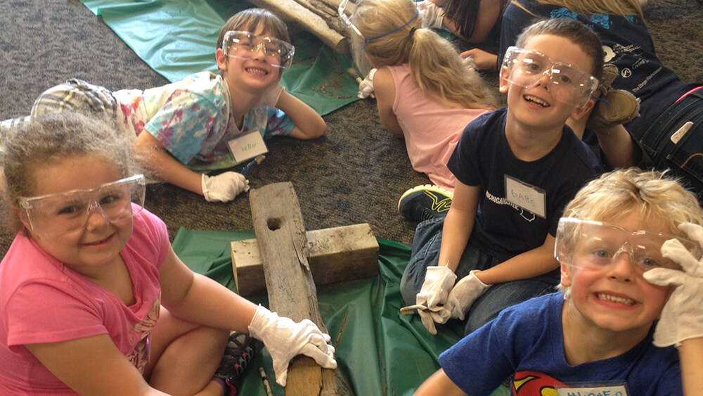 children gather around old weathered pieces of wood