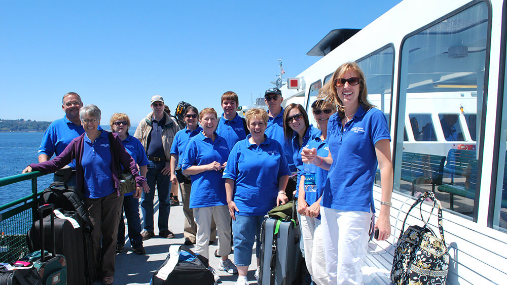 a group of people in blue shirts gathered on the deck of a ship