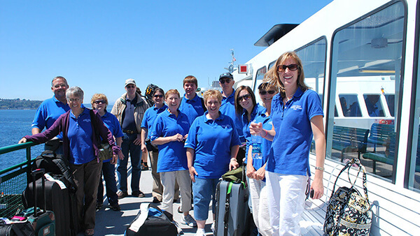 a group of people in blue shirts gathered on the deck of a ship
