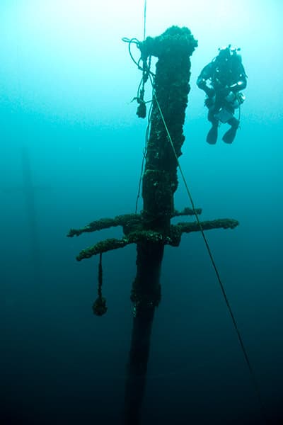scuba diver near the mast of the defiance