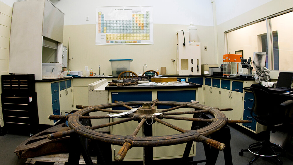an old wooden ship wheel sits in a laboratory