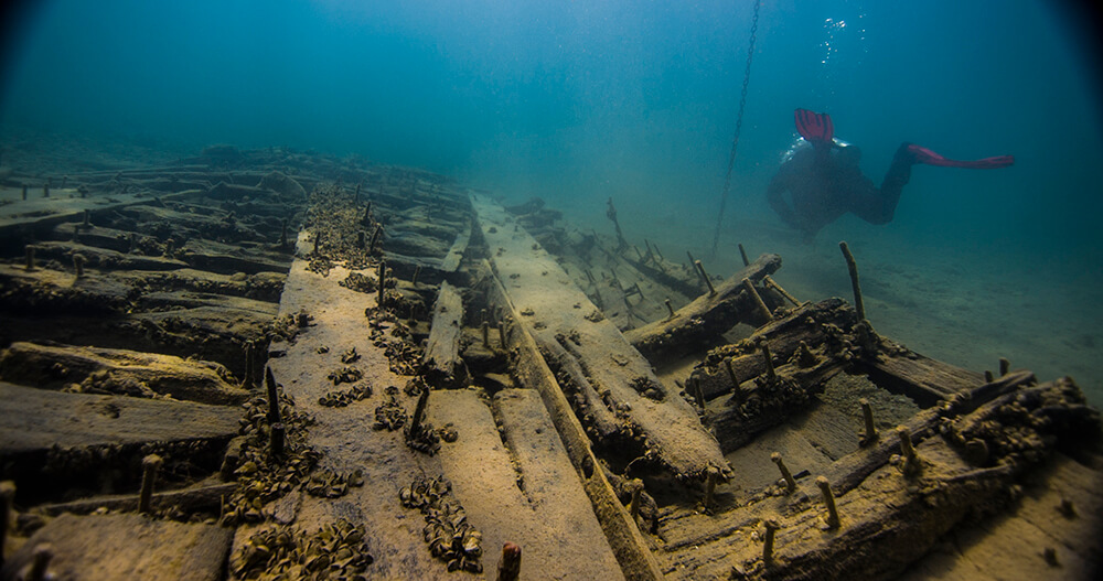 close up of a shipwreck with a diver in the background