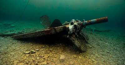 a metal piece of a shipwreck with a propeller extending from it
