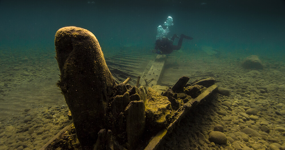 the bow of a shipwreck with a diver flaoting in the background