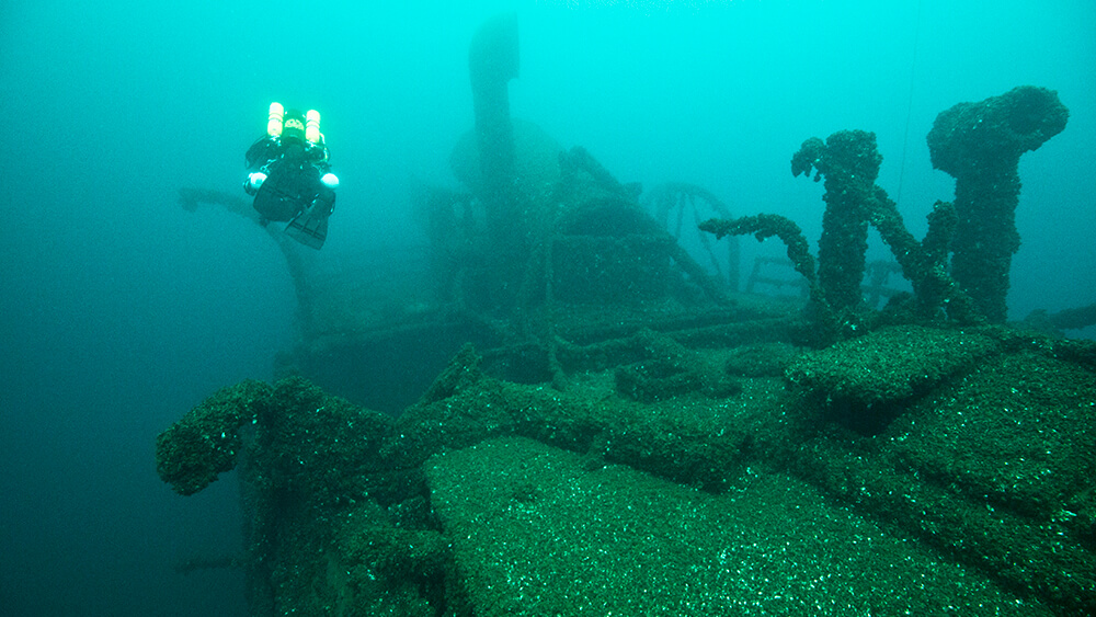 a diver swims above the deck of a shipwreck