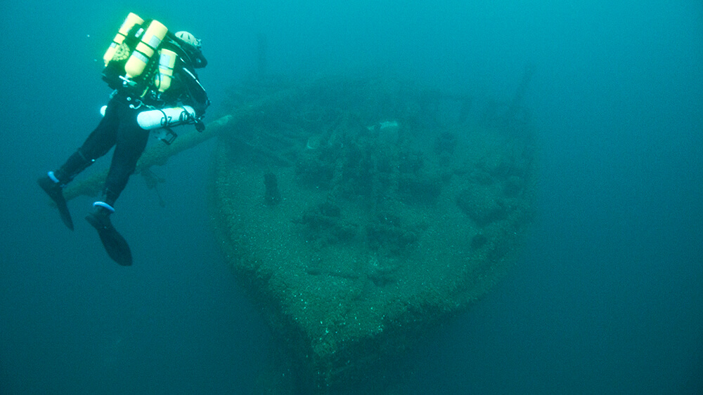 a diver descends towardss the bow of a shipwreck