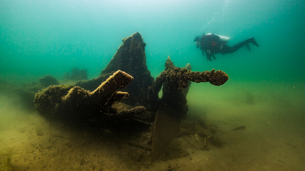 a diver swims next to a shipwreck