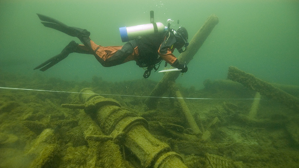 a diver swims above debris from a shipwreck