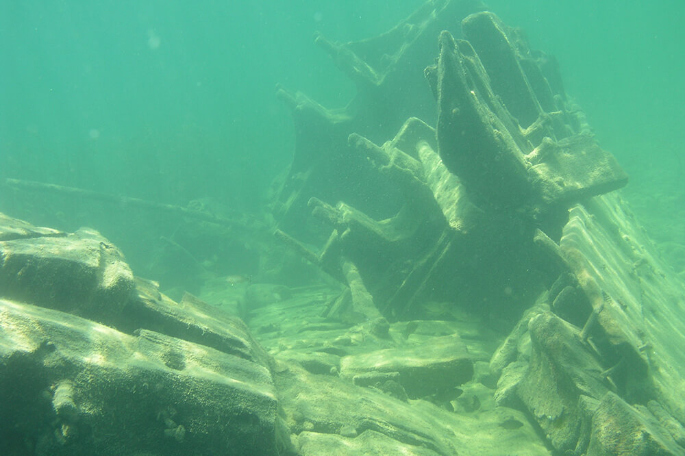A wooden shipwreck rests on its side