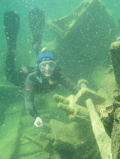 A snorkeller smiles next to a shipwreck