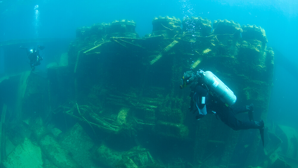 Divers swim around a shipwreck