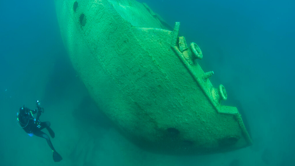 A diver photographs the hull of a shipwreck