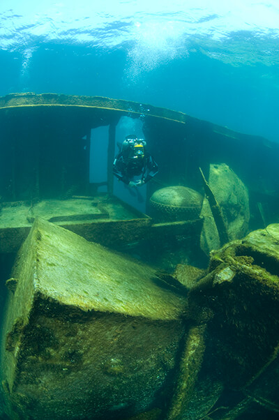 A diver swims through an opening in a shipwreck