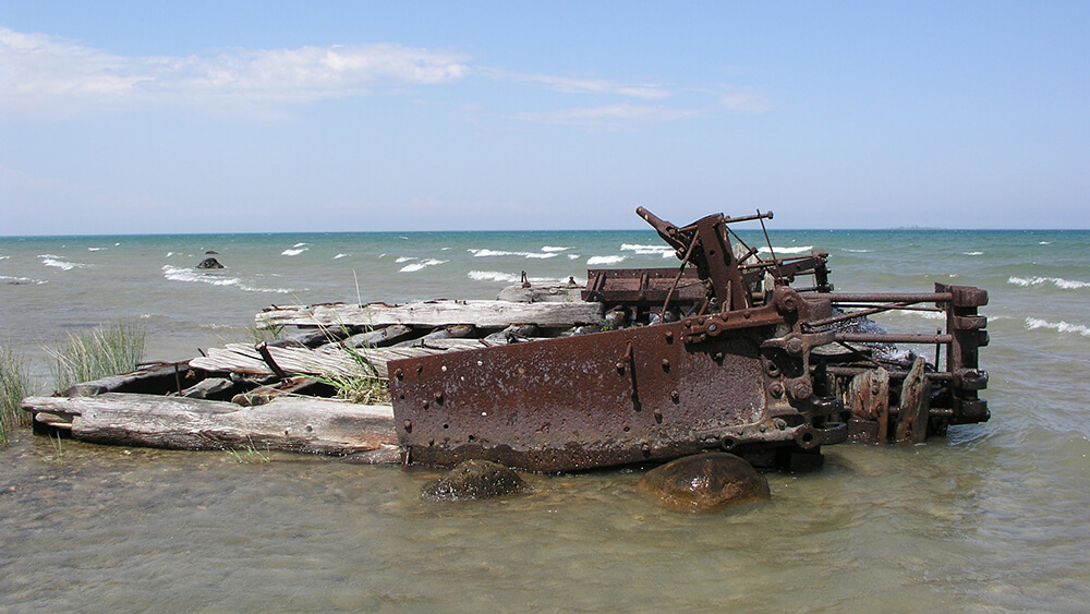 wood and metal from a ship wreck extend from shallow water
