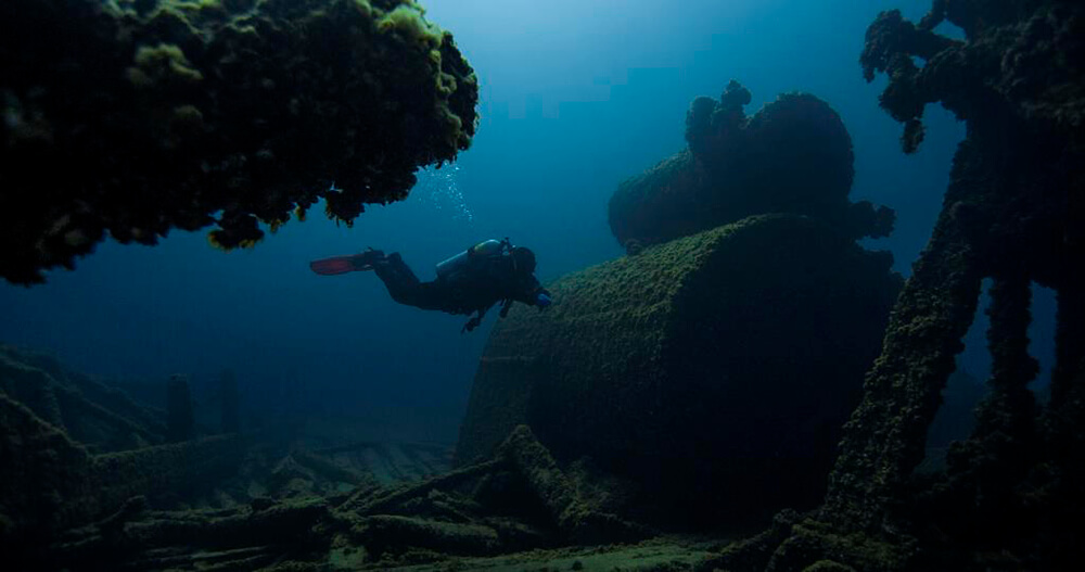 A diver swims near two cylindrical structures stacked on one another