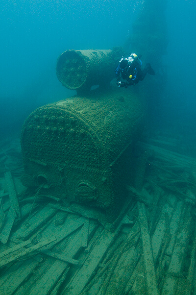 A scuba diver swims over the intact boiler that powered the wooden vessel Montana.