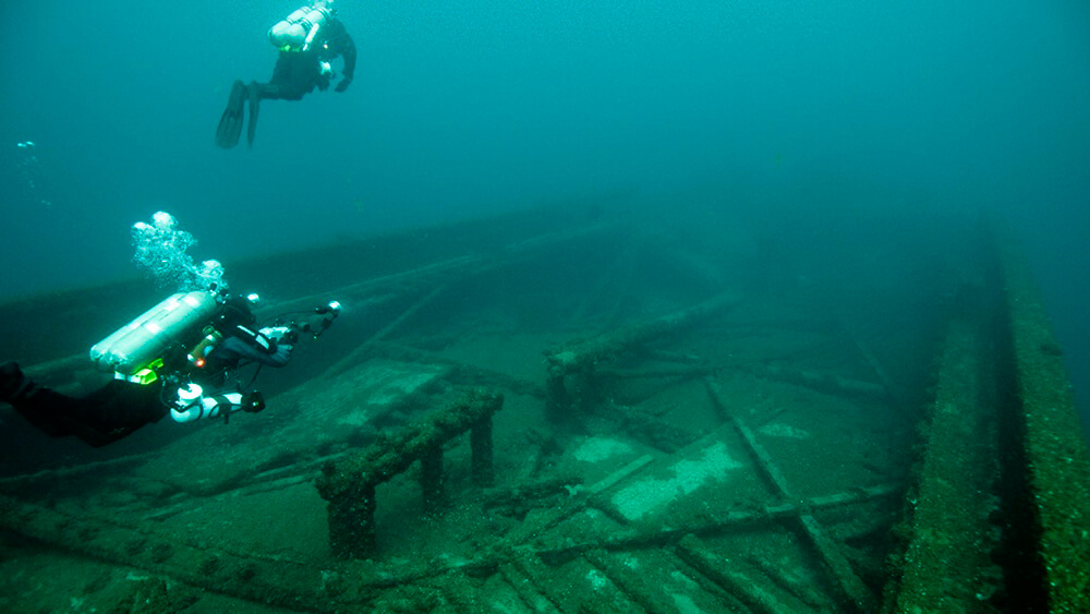 Two divera awim above a shipwreck