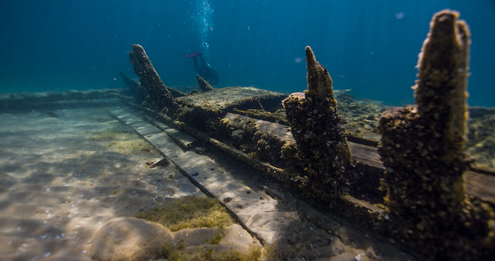 a shipwreck with a diver in the distance