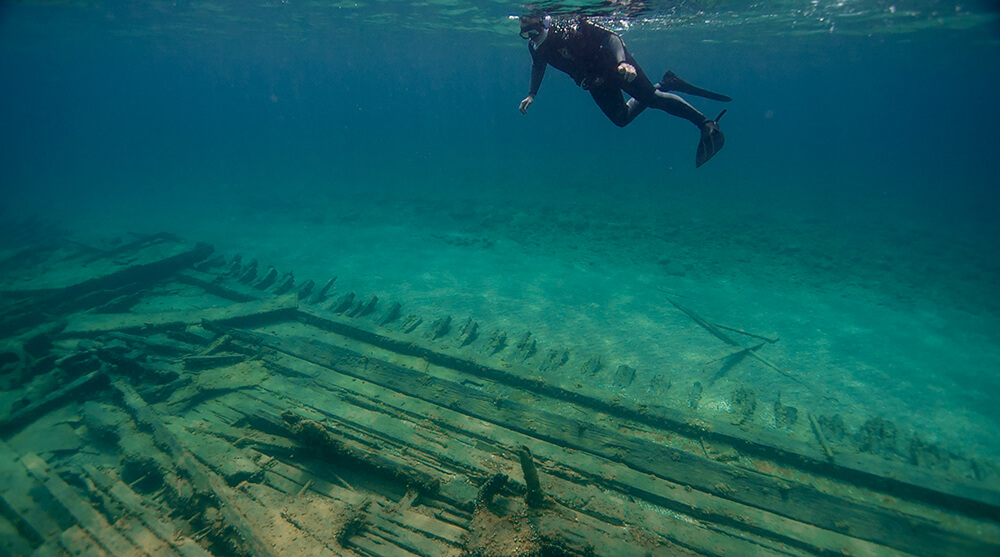 a snorkeler floats above wood planks from a shipwreck