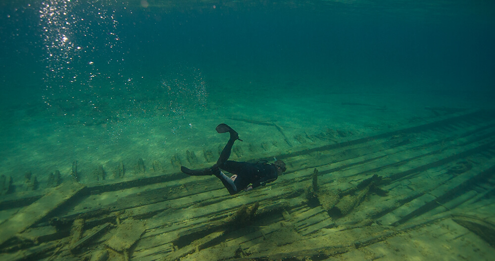 a snorkeler swims above wood from a shipwreck