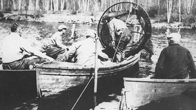 Black and white photo of people fishing from canoes