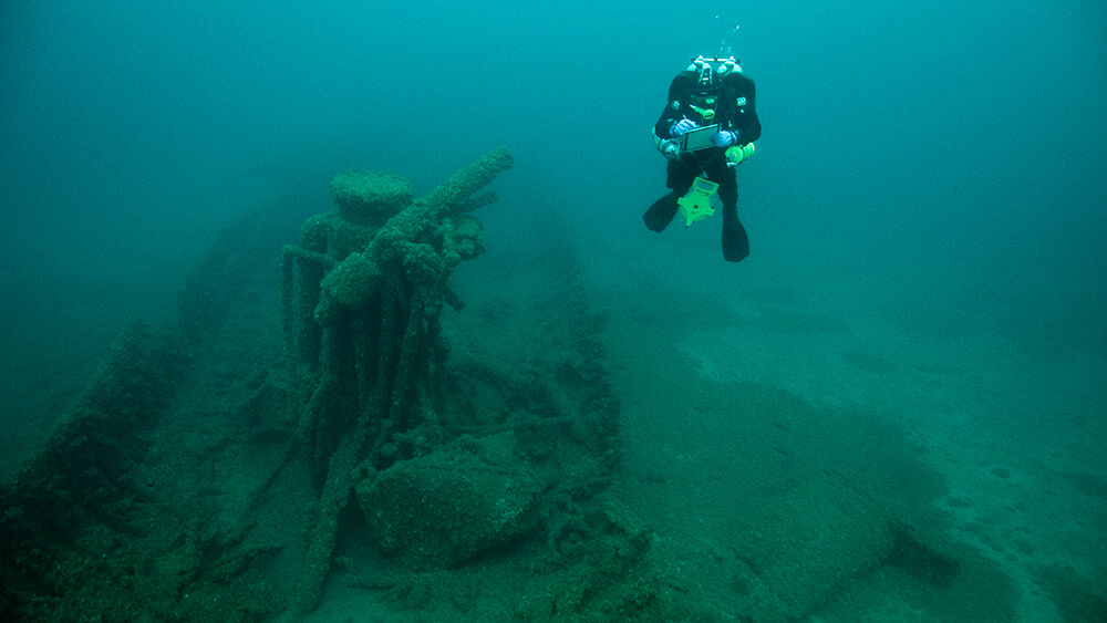 A diver takes notes next to a shipwreck