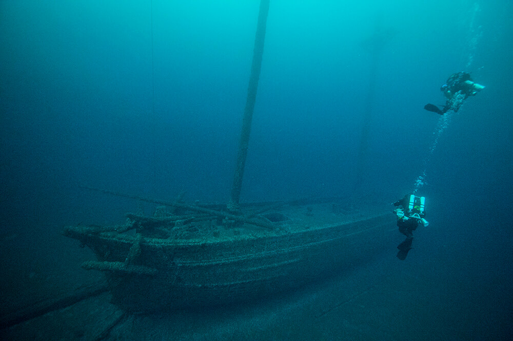 Two divers swim near a shipwreck