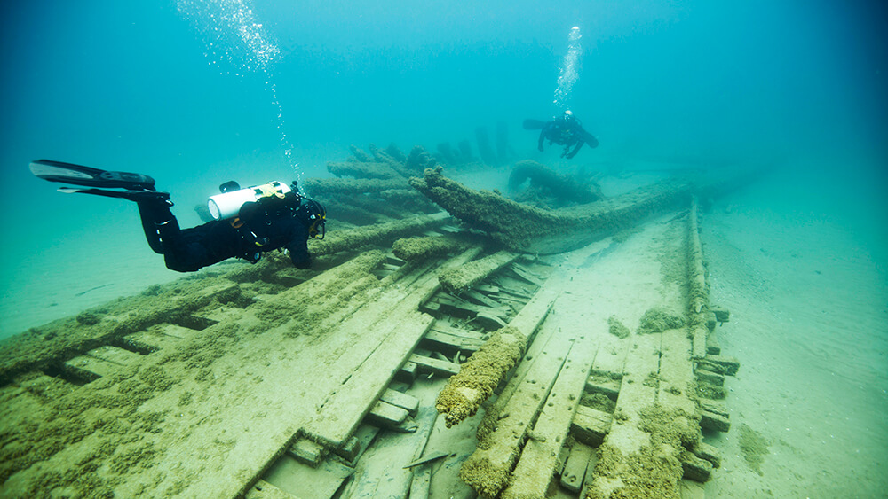 Two divers swim above a shipwreck