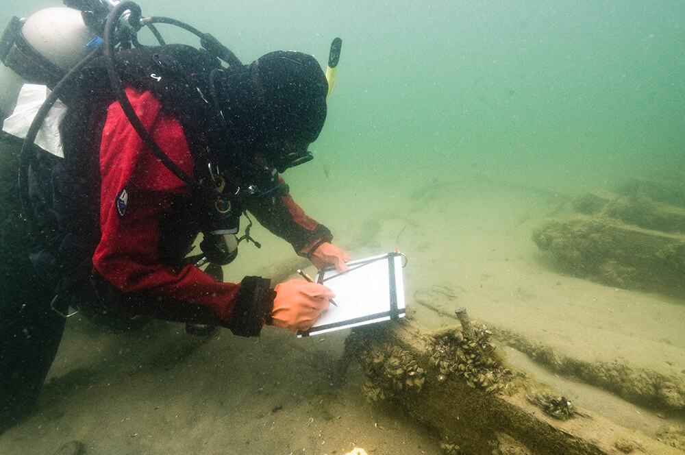 a diver takes notes while examining a shipwreck