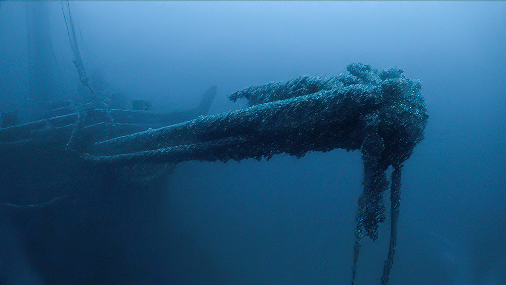 a wooden bowsprit extends from a sunken vessel, which is visible in the background
